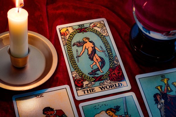 The world tarot card and crystal ball under candle light. Cartomancy is fortune telling using cards, while scrying and clairvoyance is future reading using orbs, both are branches of astrology The world tarot card and crystal ball under candle light. Cartomancy is fortune telling using cards, while scrying and clairvoyance is future reading using orbs, both are branches of astrology
